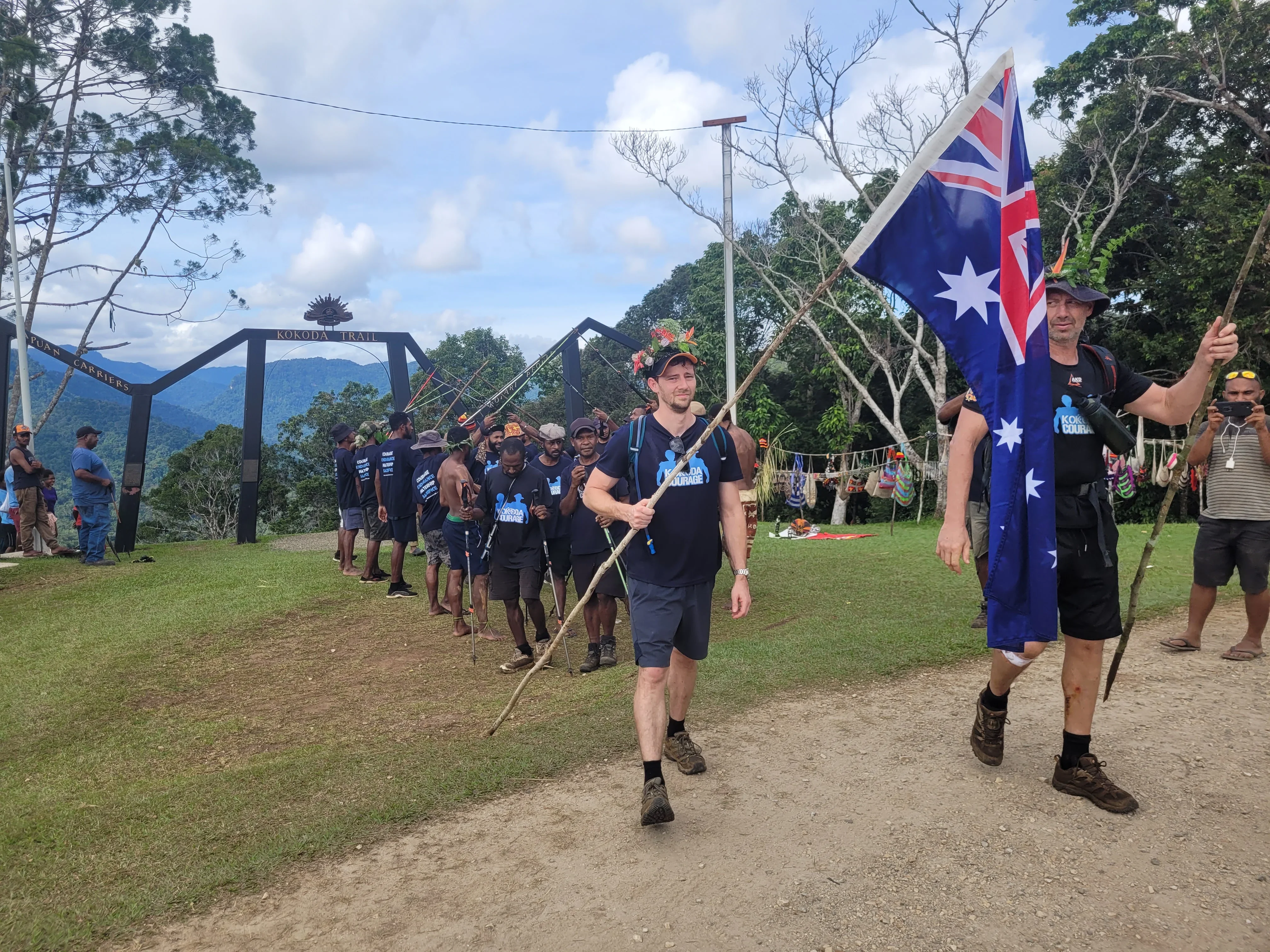 Kokoda Courage trekkers finishing at the Kokoda Trail arch with flags
